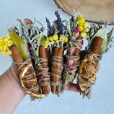 four bundles of dried herbs tied together with twine and flowers on top of each other