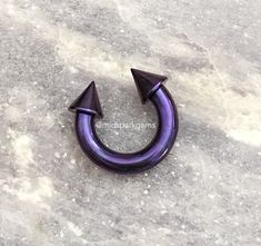 an image of a purple metal ring with two black spikes on it's side