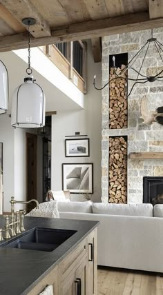 a living room filled with furniture next to a firewood stack and a stone fireplace