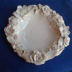 a white plate with flowers on it sitting on a blue cloth covered tableclothed surface