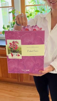 a woman holding up a pink box with flowers in it