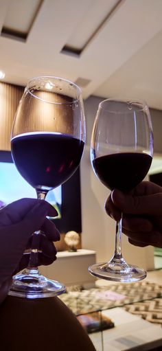 two people holding wine glasses in their hands