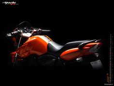 an orange and black motorcycle parked in the dark