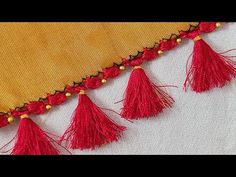 red tassels are hanging on the side of a yellow piece of cloth with gold beads