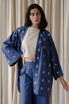 Blue full kimono sleeves shrug in organic cotton base with floral motif embroidery. Paired with sleeveless top and relaxed pleated and two patch pockets detail rayne pant.
Components: 3
Pattern: Patch Embroidery
Type Of Work: Bloom
Neckline: Top: Boat, Shrug: Open
Sleeve Type: Top: Sleeveless, Shrug: Kimono
Fabric: Organic Cotton
Color: Beige, Blue
Other Details: 
Attached inner lining
Length(in inches):
Top: 16.5
Rayne pant: 38
Model Height: 5ft 8inches, wearing size S
Occasion: Work - Aza Fash Sleeveless Shrug, Motif Embroidery, Patch Embroidery, Open Sleeve, Kimono Sleeves, Kimono Fabric, Kimono Sleeve, Top Sleeveless, Pant Set