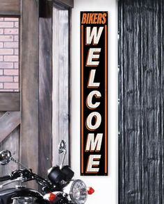 a black motorcycle parked next to a wooden door with a welcome sign on the wall