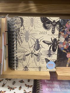 a book shelf filled with books covered in bugs and butterflies on them, next to a wall mounted clock