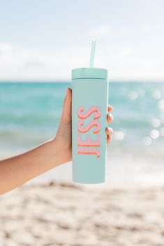 a person holding up a blue tumbler cup with the word less in pink on it