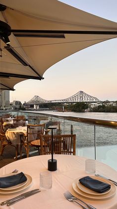 an outdoor dining area overlooking the water and bridge