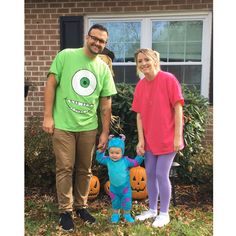 a man and woman standing in front of a house with two children dressed up as monsters