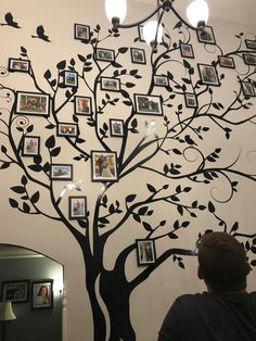 a man standing in front of a tree with many pictures on it's branches