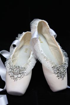 pair of white ballet shoes with bows and diaper