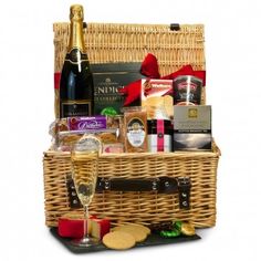 a wicker basket filled with wine, cheese and crackers next to a bottle of champagne