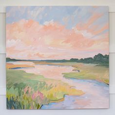 a painting hanging on the wall next to a white wall with an orange and pink sky