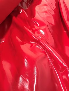 a woman laying on top of a bed covered in red plastic sheet covering it's sides