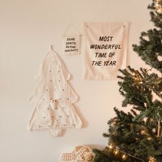 two christmas tree decorations hanging on the wall next to a small christmas tree in front of a white wall