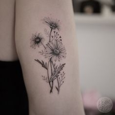 a black and white photo of a woman's arm with daisies on it