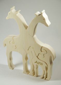 two wooden giraffes standing next to each other on a white table top