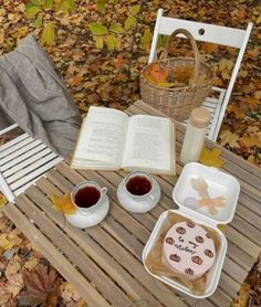 an open book sitting on top of a wooden table next to two cups of coffee