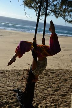 a woman is doing aerial acrobatics on the beach