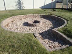 an outdoor fire pit surrounded by rocks and grass