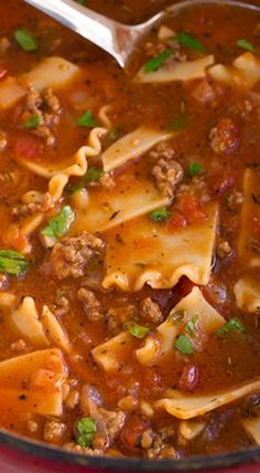 lasagna soup in a red pot with a ladle full of meat and noodles