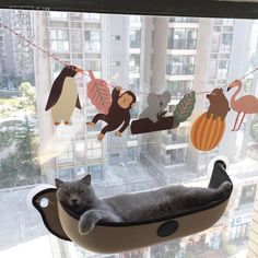 a cat is sleeping in a hammock with animals hanging from it's sides