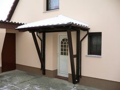 a white door and window in front of a pink house with snow on the roof