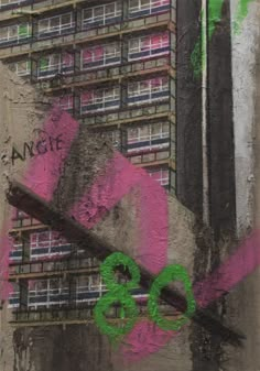 graffiti on the side of a building with pink and green spray paint in front of it