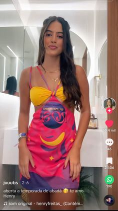 a woman in a pink and yellow bathing suit standing next to a mirror with her hands on her hips