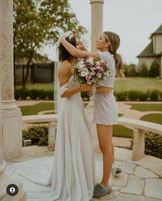 two women standing next to each other in front of a gazebo with flowers on it