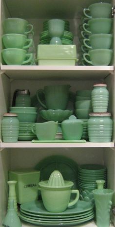 green dishes are stacked on top of each other in a cabinet with plates and cups