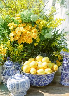 blue and white vases with yellow flowers in them sitting on a table next to lemons