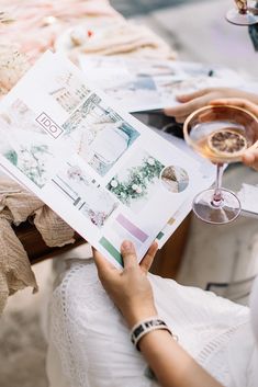 a woman holding a wine glass while sitting at a table with a menu in front of her