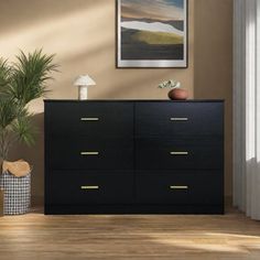 a black dresser sitting in a living room next to a potted plant