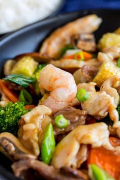 shrimp and vegetable stir fry in a black bowl