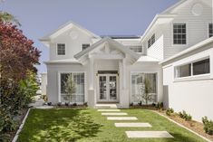 a white house with lots of windows and grass in front of the entrance to it