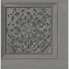 an ornate carved wood panel with leaves and flowers on it's center, in grey