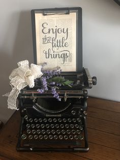 an old fashioned typewriter sitting on top of a wooden table next to a sign