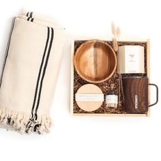 a wooden bowl and other items in a box on a white surface with a towel