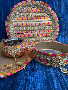 an ornately decorated platter and bowl on a blue velvet cloth with other items