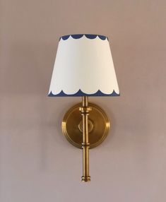 a wall light with a white shade on the top and blue scalloped lampshade