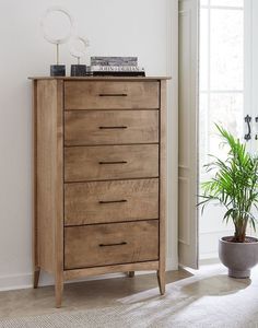 a wooden dresser sitting next to a potted plant