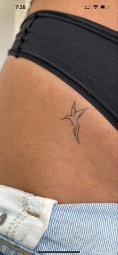 a woman's stomach with a small bird tattoo on it