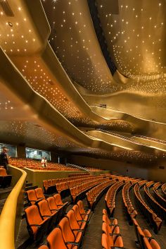 an empty auditorium with rows of orange chairs