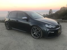 a black car parked on top of a dirt field