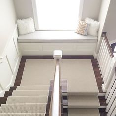 stairs leading up to a window with pillows on the windowsill and carpeted flooring