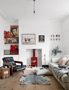 a living room filled with furniture and a fire place in the middle of it on top of a hard wood floor