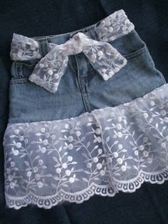 a pair of blue jean shorts with white flowers and lace on the bottom, sitting on a black surface