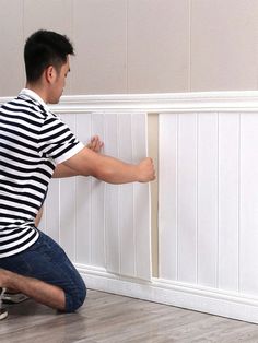 a man sitting on the floor with his feet propped up against a wall and painting it white